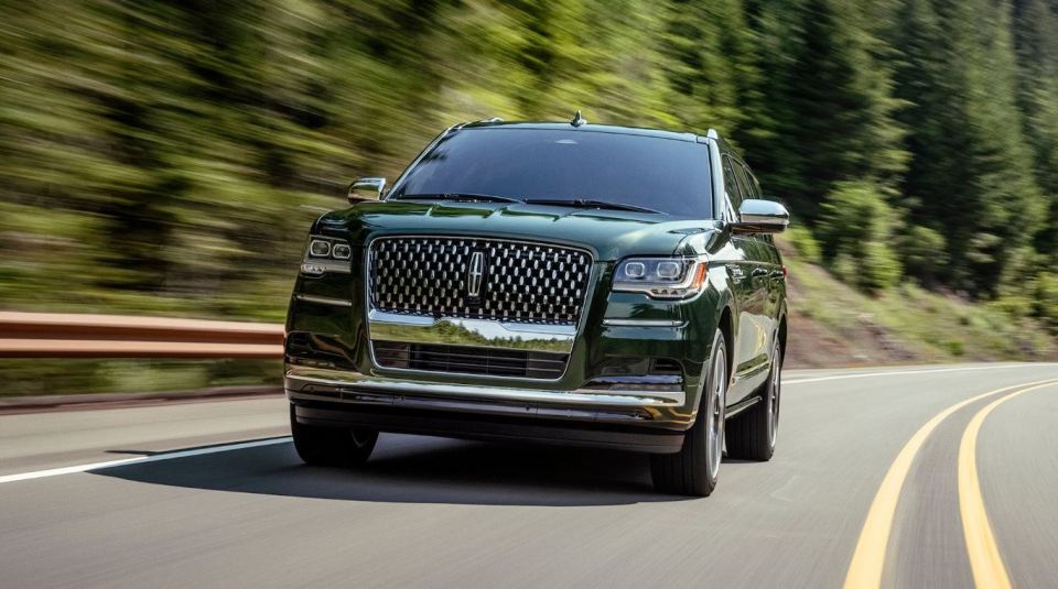 Green Lincoln Navigator driving on a road.
