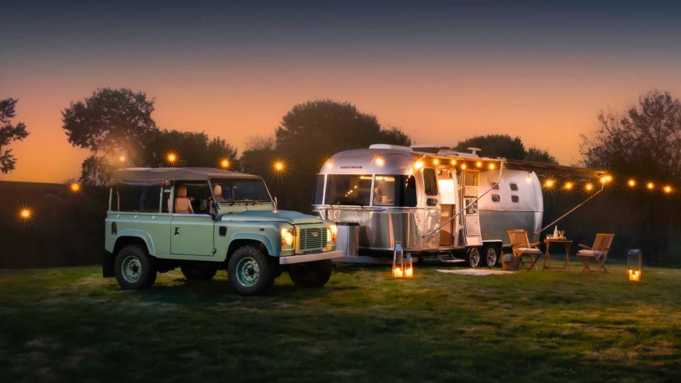 Land Rover and Airstream camper at dusk.