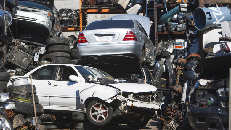 Destroyed cars stacked among tires in a junkyard
