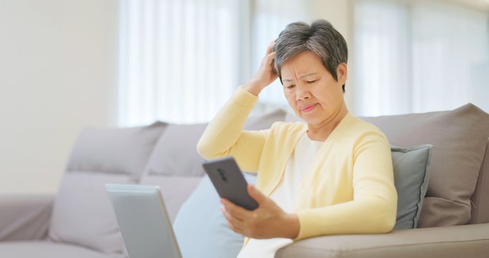An old lady looking at an iPhone. 
