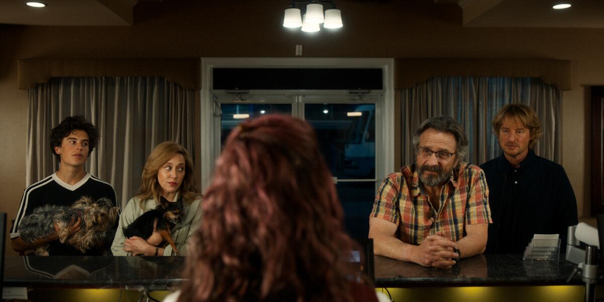 Four people sit at a long bar table.